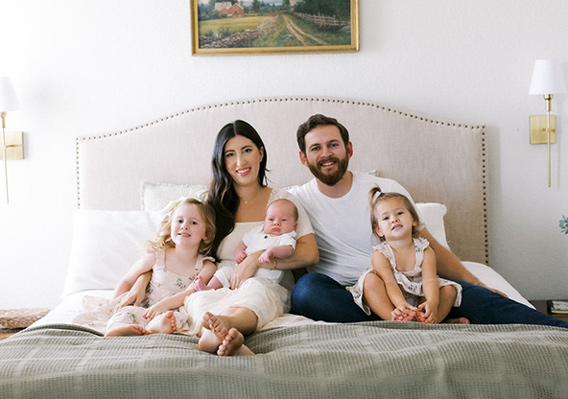 The Kobe family of 5 sitting on a bed for a family photo