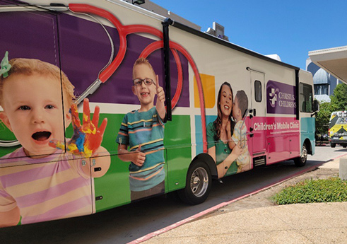 CHRISTUS Children's Mobile Clinic bus that is wrapped with images of children's