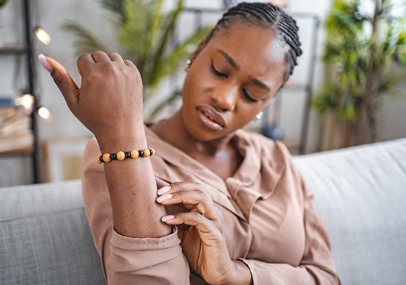 A woman is itching a bug bite or rash on her arm