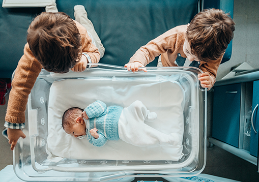 Siblings looking down at their new baby brother